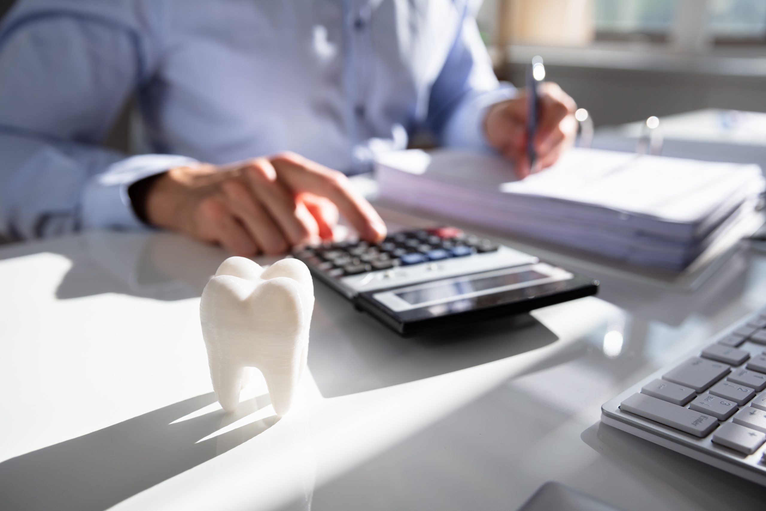 Tooth In Front Of Businessperson Calculating Bill